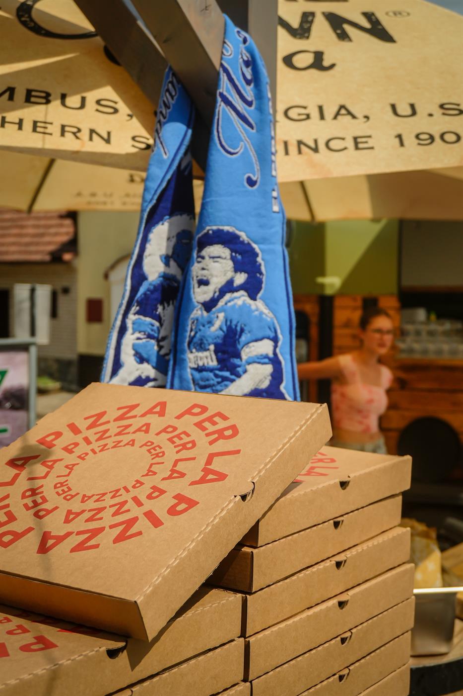 Komín krabic Per La Pizza pod šálou s Maradonou