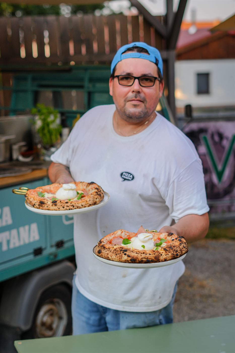Petr nese dvě pizzy s burratou od vozítka
